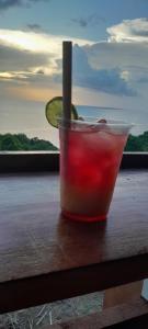 a drink sitting on a table with a view of the ocean at Coucher de soleil in Bouillante