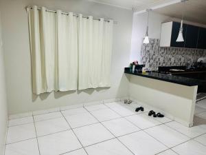 a kitchen with a white tiled floor with shoes on the floor at Quarto privativo para cop 30 in Ananindeua