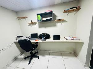 an office with a desk with a chair and a monitor at Quarto privativo para cop 30 in Ananindeua +3 photos