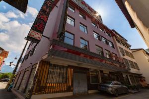 a pink building with a car parked in front of it at Hua Han Hotel in Zhangjiajie