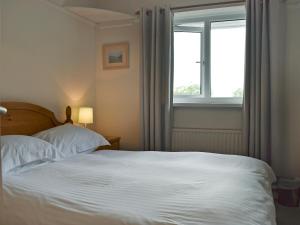 a bedroom with a white bed and a window at Manesty in Applethwaite +3 photos