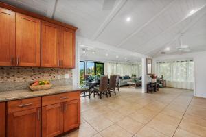 a kitchen with wooden cabinets and a living room at International Colony Club 37 · ICC 37 Remodeled Hawaiian Cottage in Kaanapali
