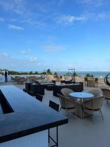 a patio with tables and chairs and the beach at Imperial Flat in João Pessoa