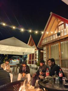 a group of people sitting around a fire at night at Parvati valley cottages & cafe in Tosh +22 photos