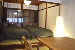 a room with two beds and a table and a table sidx sidx sidx at Hidasumika Daimon Cozyan in Takayama