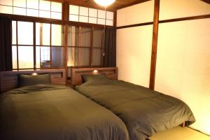 a bedroom with two beds in front of a window at Hidasumika Daimon Cozyan in Takayama