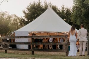 a bride and groom standing in front of a white tent at Raygold Park Equestrian Accommodation plus Pool House in Moorooduc +50 photos