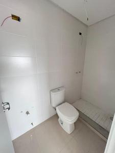 a white bathroom with a toilet and a shower at Residencial Palazzo in Tramandaí +1 photo