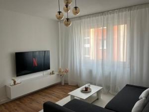 a white living room with a tv and a couch at Gemütliche, zentrale Wohnung nahe Uni & Düsseldorf in Niederdorla