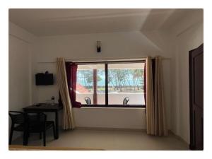 a room with a window with a table and a table and chair at Relax inn cherai beach in Cochin