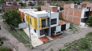 een geel en wit huis met een auto ervoor geparkeerd bij Hospedaje El Caminante CAPI in Capitanejo