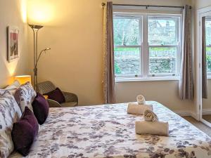 a bedroom with a large bed with two windows at 2 Greta Grove House in Keswick