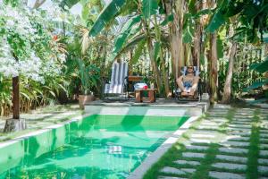 a man sitting in a chair next to a swimming pool at Mantra Yoga Homestay in Tanjung