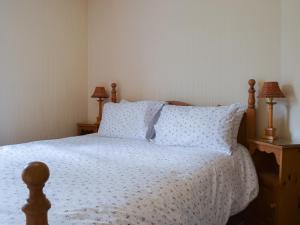 a bedroom with a bed with a white bedspread and two lamps at Valentine Cottage in Keswick