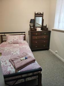 a bedroom with a bed with a dresser and a mirror at Murray's Bed & Breakfast in Gnowangerup