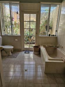 a bathroom with a tub and a toilet and windows at Murray's Bed & Breakfast in Gnowangerup
