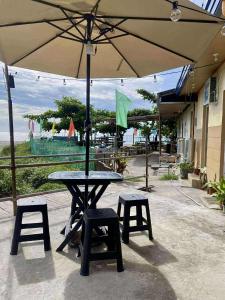 a picnic table with two stools and an umbrella at San Juan ELYU Beachfront Cabin in San Juan +10 photos