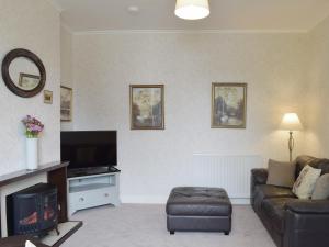 een woonkamer met een bank en een tv bij Tarn House in Wooler