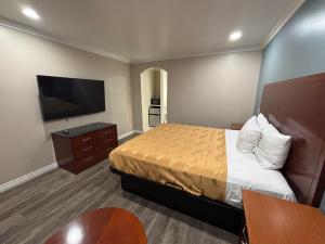 a hotel room with a bed and a flat screen tv at Economy Inn - Burbank Airport in Sun Valley +9 photos