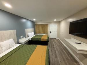 a hotel room with two beds and a flat screen tv at Economy Inn - Burbank Airport in Sun Valley