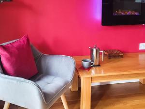 a living room with a chair and a wooden table at Cartws-Oh3 in Dihewid