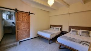 Un dormitorio con dos camas y una puerta con lavabo. en Hotel Colonial Guanajuato, en Guanajuato