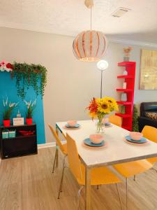 a dining room with a table and chairs with flowers at 2 Bedrooms Private Kitchen Livingroom Robinwood Condo Suite in Norcross