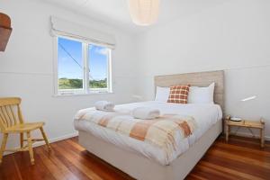ein weißes Schlafzimmer mit einem Bett und einem Fenster in der Unterkunft The Beach Cottage - Close to Beach and Town in Tairua