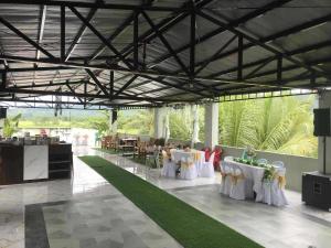 a banquet hall with white tables and chairs and plants at American Roadhouse Hotel and Restaurant in Candijay