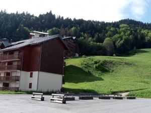 eine Gruppe von Bänken auf einem Parkplatz neben einem Gebäude in der Unterkunft Studio cosy à St Jean d'Aulps, au pied des pistes - FR-1-573-146 in Saint-Jean-dʼAulps