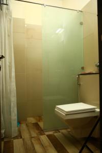 um banheiro com vaso sanitário e uma porta de vidro em Hotel Manas Plus em Khandwa