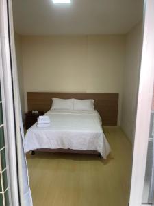 a bedroom with a white bed with a wooden headboard at Apartamento in Viçosa