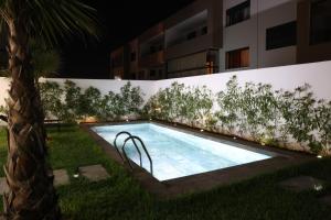 达布阿扎Dar Bouazza Luxury apartment with pools garden sports courts parking near the sea的一座建筑物旁草地上的游泳池