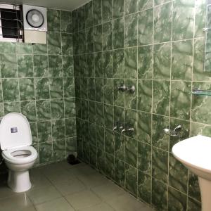 a green tiled bathroom with a toilet and a sink at Maya Eco Guest House in Dhaka +39 photos