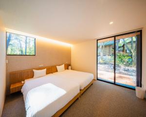 a bedroom with a large bed and a large window at Kamuy Chalet Hakuba by Jade Group in Hakuba