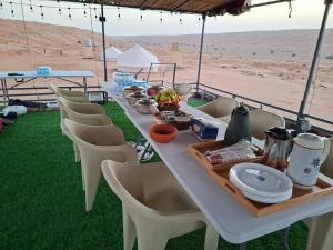 a long white table with chairs and food on it at Desert Romance Retreat in Muntarib
