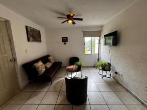 a living room with a couch and a ceiling fan at Las Fuentes in Mérida