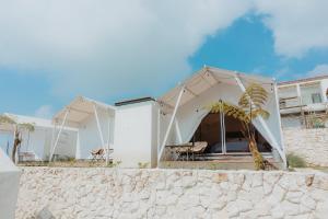 a white house with a tent on the beach at HappyNest Glamping and Villa Dieng in Garung