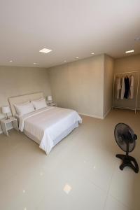 ein Schlafzimmer mit einem großen weißen Bett und einem Stuhl in der Unterkunft Village GRAND LUX exclusivo com piscina privativa in Feira de Santana