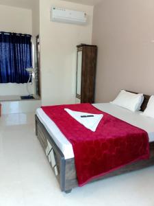 a bedroom with a bed with a red blanket on it at hotel shreejee in Himatnagar