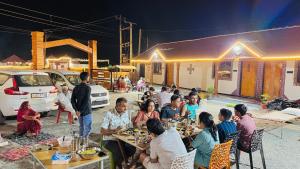 a group of people sitting at tables eating food at Holiday Homestay dholavira 