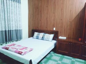 Nhà nghỉ Việt Hà - ĐH Công nghiệp TN : غرفة نوم بها سرير وجدار خشبي