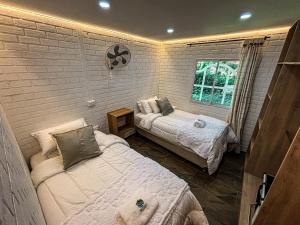 a bedroom with two beds and a brick wall at Cabañas betania in Santa Marta +6 photos