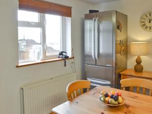 a kitchen with a wooden table with a bowl of fruit at Ponsgwedhen in Coverack