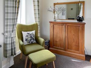 a green chair with a pillow and a mirror at Kirnan Cottage in Kilmichael Glassary