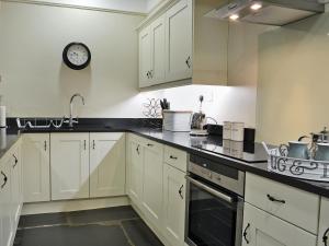 een keuken met witte kasten en een klok aan de muur bij Fellmere in Ambleside +7 foto's
