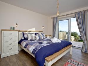 a bedroom with a bed and a large window at Orestone Garden Apartment in Dawlish