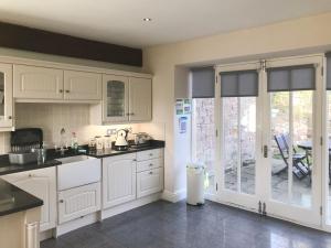 a kitchen with white cabinets and a sliding glass door at Murton Cottage in East Ord