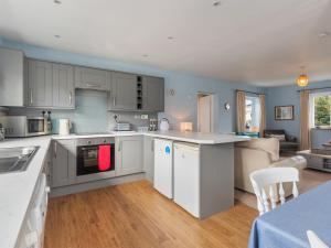 a kitchen with white cabinets and a living room at Min Y Traeth By The Beach in Morfa Nefyn +18 photos