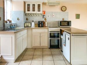 a kitchen with white cabinets and white appliances at Hideaway in Brompton Ralph